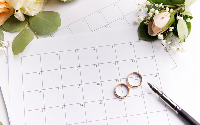 two wedding rings placed on top of a calendar with wedding flowers