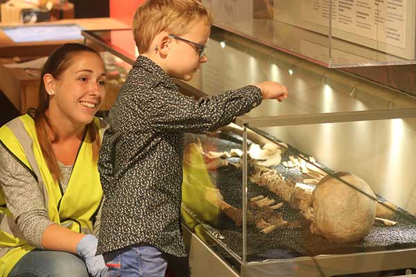 a guide helping a child view a skeleton in the museum